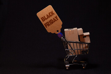 Mini cart loaded with packages and Black Friday sign, retail and e-commerce on dark background