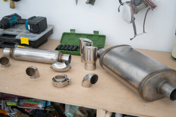 Exhaust system parts are arranged on a workbench, displaying various components for service,...