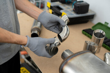 Worker fits together stainless steel elbow pipe joints using gloves in a well-organized workshop....