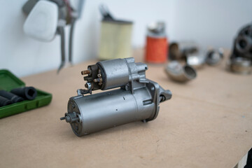 A new car starter on a table surrounded by tools, indicating a home automotive repair project in...