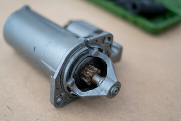 A new car starter on a table surrounded by tools, indicating a home automotive repair project in...