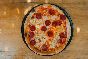 Tasty Italian pepperoni pizza on wood table. Pepperoni pizza on rustic background. Freshly baked pepperoni pizza on wood surface.