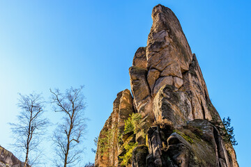 Majestic rock formation against clear blue sky with leafless trees