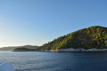 Obraz premium Beautiful island landscape at sunset with lush, thick woodland and turquoise tropical waters. Mountains, dense green forests, white rocks and clear blue waters make up the idyllic travel destination.