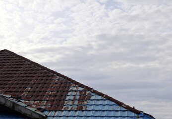 old rusty metal roof with cloudy blue sky as background