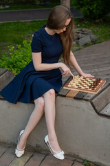 Caucasian woman playing chess outdoors.