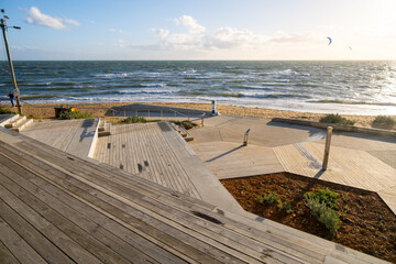 Modern outdoor plaza with tiered wooden decking and stairs providing seating and access to beach at Melbourne’s coastline, overlooking the ocean. Coastal infrastructure at Brighton Beach, Australia.  © Doublelee