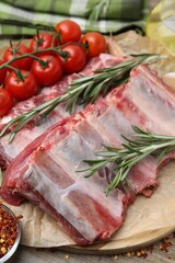 Fresh raw beef ribs, tomatoes and spices on table, closeup