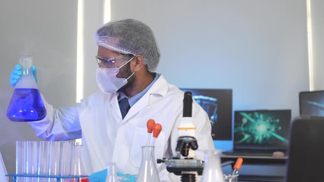 A research scientist works late in the lab, using a microscope to analyze samples. His bench is filled with glassware from an ongoing and complex chemical experiment.
