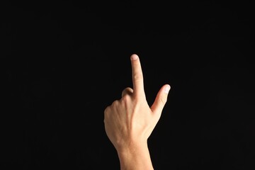 Man touching something on black background, closeup