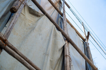 足場丸太を番線で固定して遮蔽シートを掛けた様子