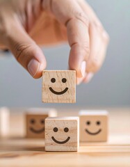 Hand placing a wooden block with a smiley face on top of others