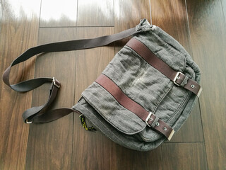 使い込まれたショルダーバッグが床に置かれている風景