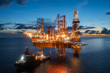 Aerial view of offshore jack up rig and offshore platform during sunset for oil and gas exploration and production.