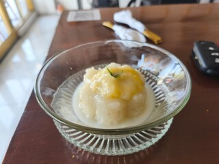 Traditional Thai dessert of sticky rice topped with durian and coconut milk, served in a glass bowl with a golden fork.
