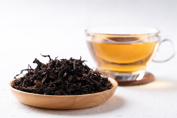 Dried black tea leaves and hot tea in cup glass on white background, Healthy herbal drink