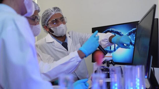 A team of geneticists collaborates on a gene sequencing analysis. The lead researcher points to a 3D model of a DNA helix, discussing specific loci with colleagues.