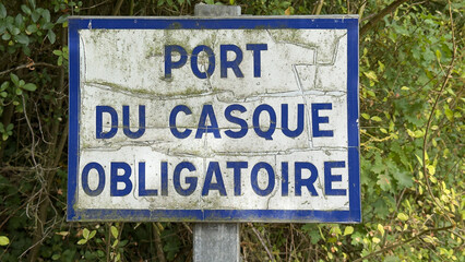Weathered french sign stating that helmets are mandatory, port du casque obligatoire