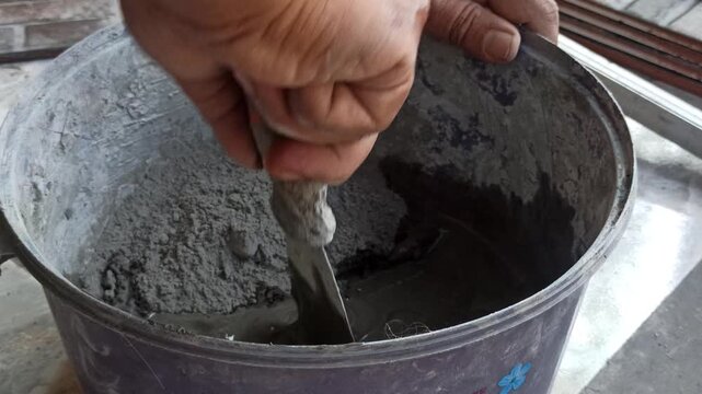 Mixing cement for wall tiles, showcasing construction process, precise preparation, and ready-to-use mortar for tiling work in modern or traditional interiors.