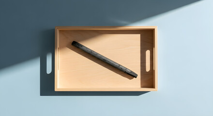 Single charcoal  stick in a light wood tray against a blue  with shadows