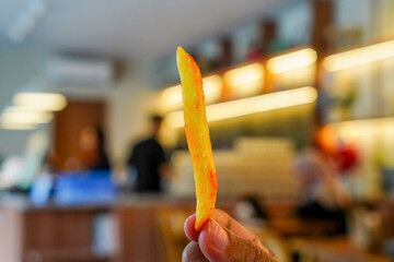 Holding single french fry in restaurant setting for fast food ads