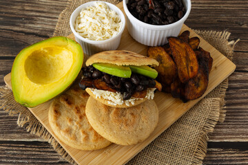 Arepa rellena with caraotas negras, fried ripe plantains, avocado, and shredded cheese
