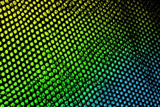 Abstract gradient pattern of vibrant green, yellow, and blue circles on black