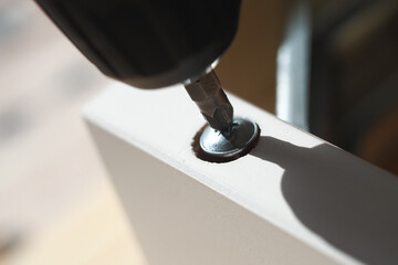 Screw driver attaching metal screw to wooden piece