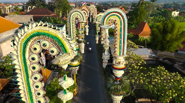 Colorful Penjor decorations line a village street in Bali during the Galungan celebration, symbolizing prosperity and gratitude in Balinese Hindu tradition.
