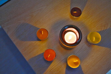 Colorful Tealight Candles Burning on a Wooden Table in the Dark