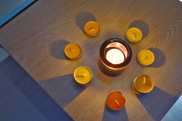 Colorful Tealight Candles Burning on a Wooden Table in the Dark