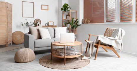 Interior of modern living room with grey sofa and laptop on wooden coffee table