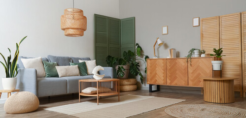 Interior of modern living room with grey sofa, green folding screen and coffee table