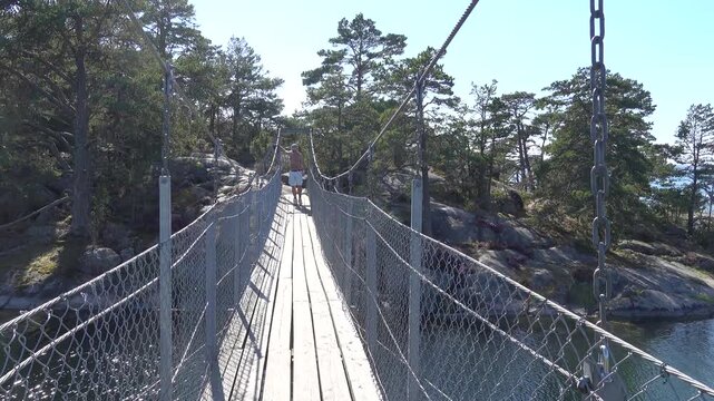 Stendorren, Sweden A man walks over a pedestrian bridge in the Stendorren Nature Reserve to a rocky island in the Baltic Sea.