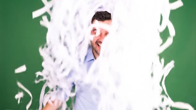 Man in blue shirt ecstatically shouts, confetti flying on green backdrop