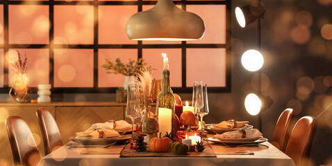 Festive table setting with burning candles, pumpkins and greeting cards for Thanksgiving Day at...