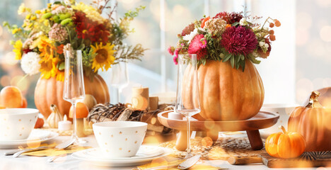 Festive table setting with bouquets of autumn flowers in pumpkins