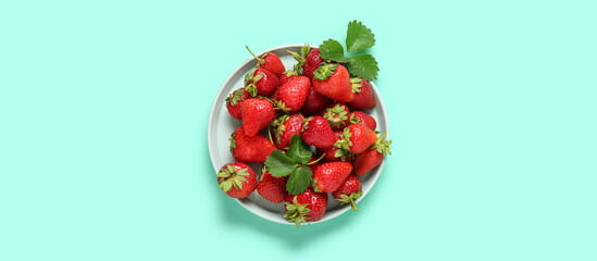 Plate with fresh ripe strawberries on turquoise background