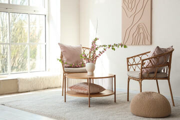 Chairs and coffee table with vase and blooming branches in living room
