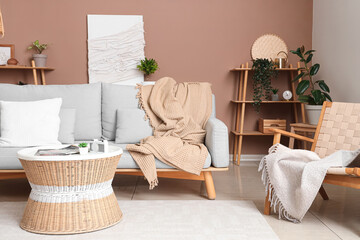 Stylish interior of living room with cozy sofa, armchair, coffee table and plaid