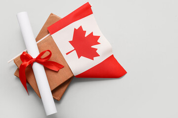 Diploma with red ribbon, books and Canadian flag on white background