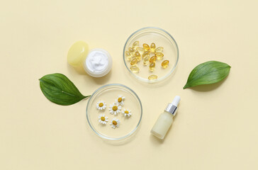 Bottles of products and Petri dishes with ingredients for preparing natural cosmetics on yellow background