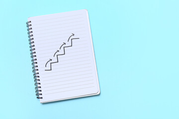 Notebook with drawn ladder and arrows on blue background