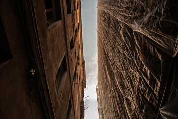 Upward view on narrow apartment blocks in Valencia Ciutat Vella, in spain, one draped in crinkled...