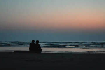 teenage boy finds solace in supportive presence of his friend as they sit together on beach
