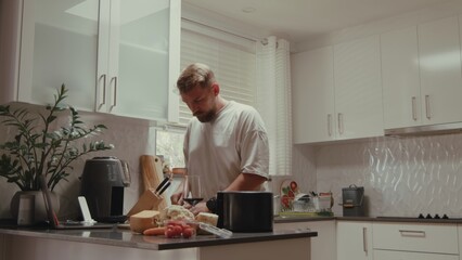 Caucasian man, 35 years old, focused on preparing food in serene kitchen. Cutting vegetables, using air fryer, enjoying calm daytime atmosphere.