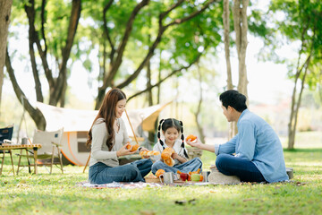 Happy parents and daughter Bakery and Bread Fruit enjoy  in a sunny garden. A joyful summer picnic...