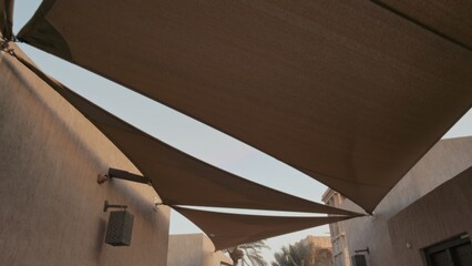 Three triangular shade sails provide coverage in a calm residential courtyard. Serene outdoor setting enhances peaceful atmosphere during daytime.