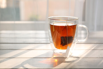 Glass cup of black tea on table near window
