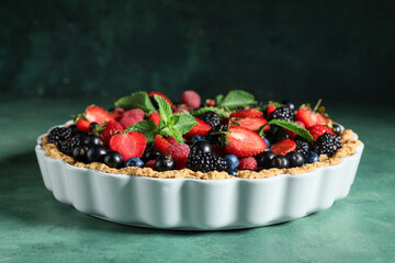 Sweet tart with different fresh berries and mint on green background
